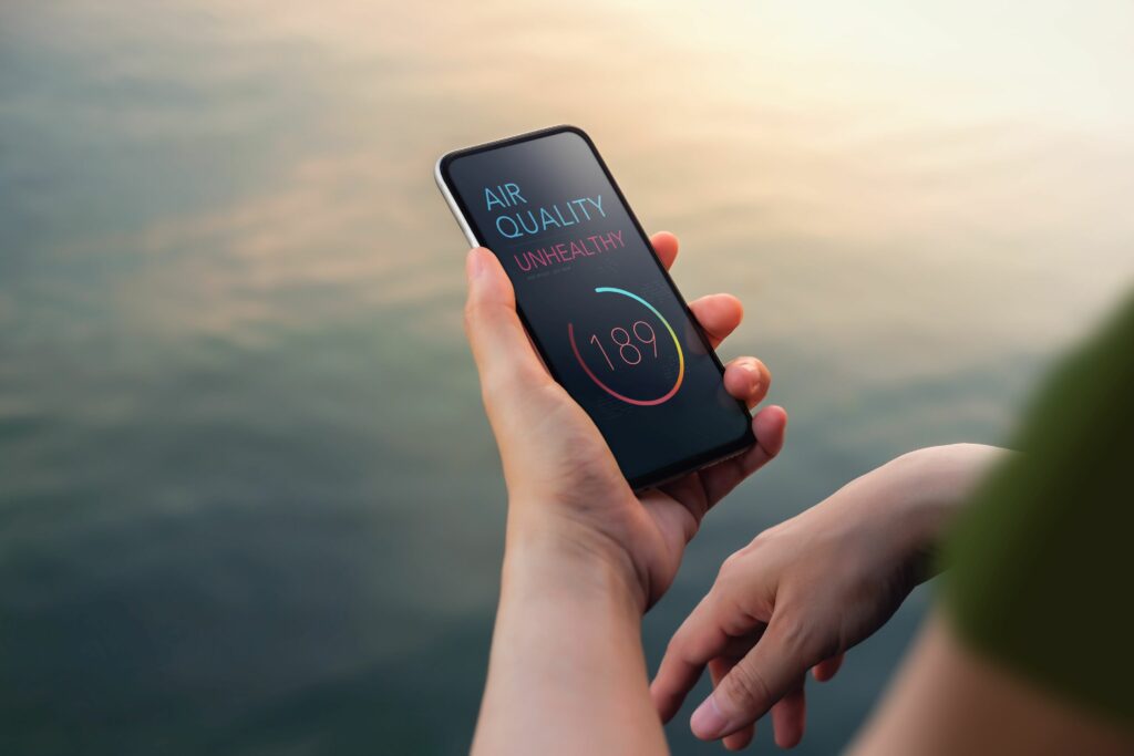 Air Pollution, Weather and Environment Issue Concept. Woman Using Mobile Phone to Check Air Quality as Unhealthy at the Riverside. Top View